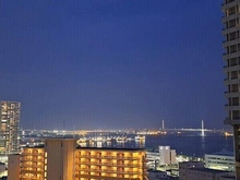 【神奈川県/横浜市神奈川区栄町】ザ・ヨコハマタワーズ　タワーウエスト 外観：日没後のバルコニーからの横浜港・横浜ベイブリッジです。室内からは真ん中の洋室が一番綺麗に見えます